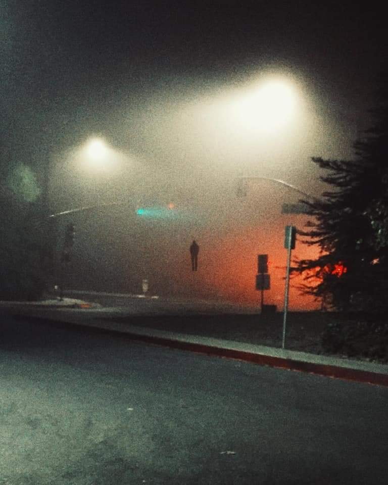 The meme is a humorous image of a dark and empty road at night, with a faint figure of a person in the distance. The image is captioned "when you're walking home alone at 2am and you hear footsteps behind you". The tone is ominous and playful, implying that the person is being paranoid and expects something to happen, but nothing actually does.